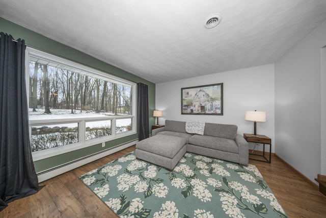 living room with wood finished floors, baseboards, baseboard heating, and visible vents