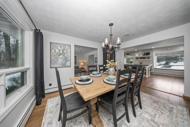dining area featuring baseboard heating, hardwood / wood-style flooring, and a chandelier