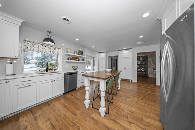 kitchen with white cabinetry, wood finished floors, stainless steel appliances, and a sink