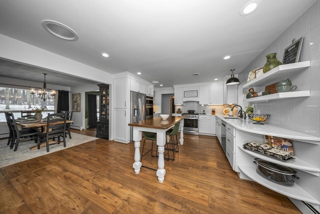 kitchen with a sink, an inviting chandelier, white cabinetry, open shelves, and appliances with stainless steel finishes