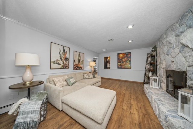 living room with a baseboard heating unit, baseboards, wood finished floors, and crown molding
