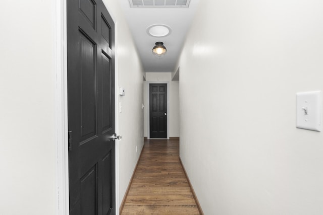 hallway with wood finished floors, visible vents, and baseboards