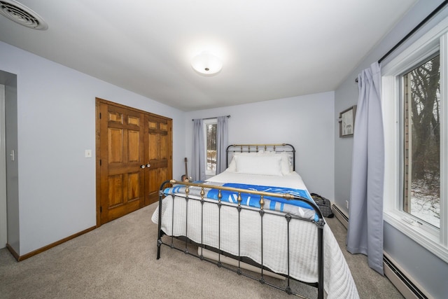 carpeted bedroom featuring baseboard heating, baseboards, and visible vents