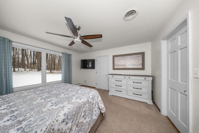 bedroom with light carpet, baseboards, visible vents, a ceiling fan, and a baseboard radiator
