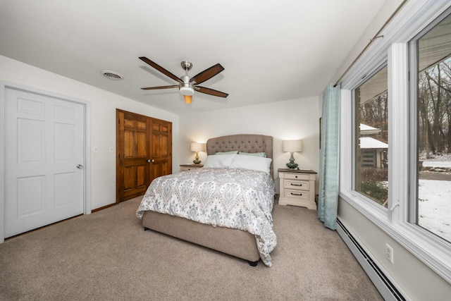 carpeted bedroom featuring ceiling fan, visible vents, a baseboard radiator, and multiple windows