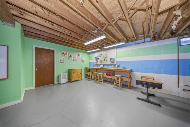 interior space with concrete block wall, baseboards, a workshop area, and finished concrete flooring