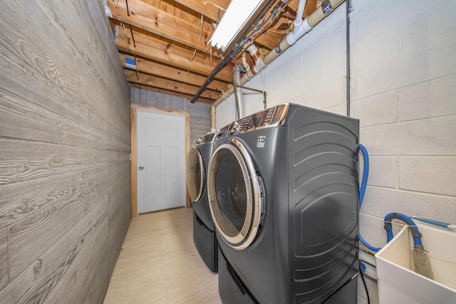washroom featuring independent washer and dryer, concrete block wall, and laundry area