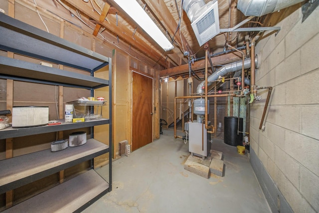 unfinished below grade area with concrete block wall, visible vents, and a heating unit