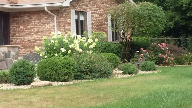 view of side of property with fence, a lawn, and brick siding