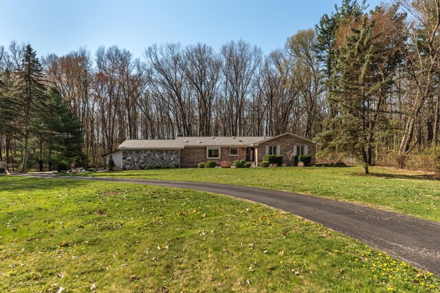 ranch-style home featuring a front lawn and stone siding