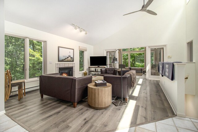 5410 Oak Ridge Rd, Ludington, MI 49431 - living area featuring baseboard heating, a tiled fireplace, ceiling fan, high vaulted ceiling, and wood finished floors