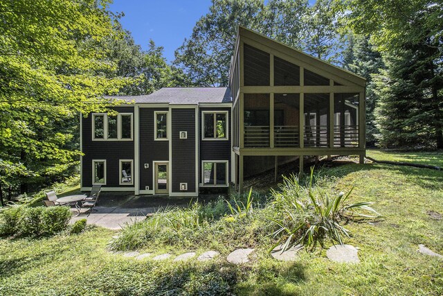 5410 Oak Ridge Rd, Ludington, MI 49431 - rear view of house with a sunroom, a patio area, and a lawn