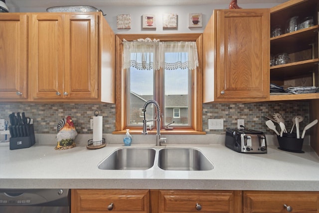 kitchen featuring tasteful backsplash, dishwasher, light countertops, and a sink