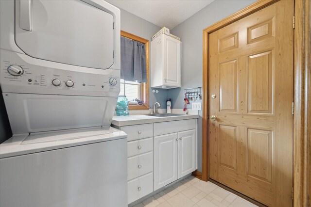 laundry room featuring stacked washer / dryer, a sink, and cabinet space