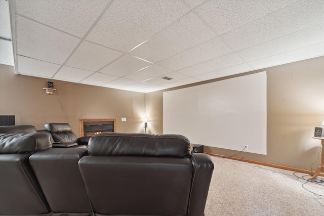 home theater with a glass covered fireplace, carpet, a drop ceiling, and baseboards