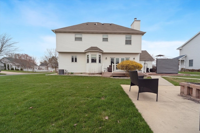 back of property with a chimney, a patio area, central AC, a yard, and a deck