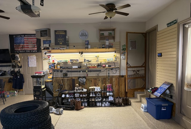 interior space featuring a garage door opener, a workshop area, and a ceiling fan