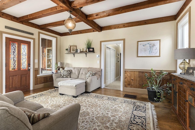 living area with beamed ceiling, wooden walls, wood finished floors, and wainscoting