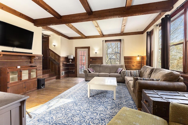 living area featuring wainscoting, light wood-style flooring, a wealth of natural light, and beamed ceiling