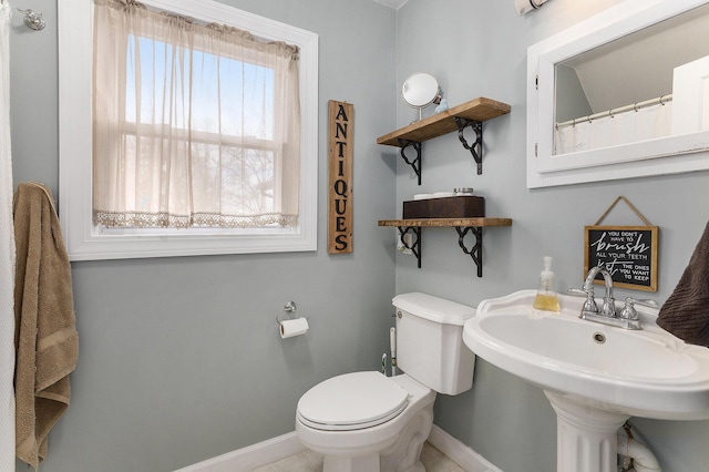 bathroom featuring baseboards, toilet, and a sink