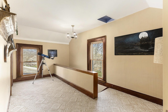 hallway with baseboards, lofted ceiling, a notable chandelier, and carpet
