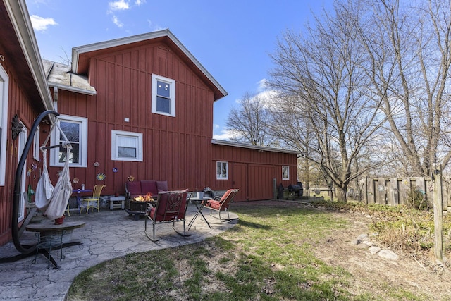 rear view of property featuring a yard, an outdoor living space, a patio area, and board and batten siding