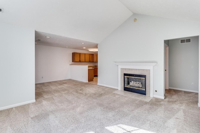 unfurnished living room featuring visible vents, a fireplace, recessed lighting, high vaulted ceiling, and light colored carpet