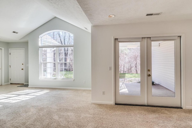 entryway with vaulted ceiling, french doors, visible vents, a healthy amount of sunlight, and carpet