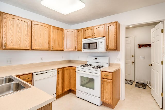 kitchen featuring white appliances, light countertops, a sink, and light tile patterned flooring