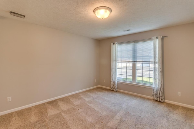 carpeted spare room featuring a textured ceiling, baseboards, and visible vents