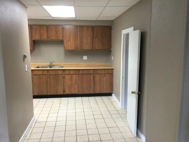 201 E Danaher St, Ludington, MI 49431 - kitchen with brown cabinets, a paneled ceiling, light countertops, and a sink