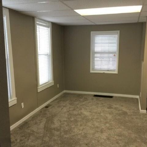 201 E Danaher St, Ludington, MI 49431 - spare room featuring visible vents, a drop ceiling, baseboards, and carpet floors