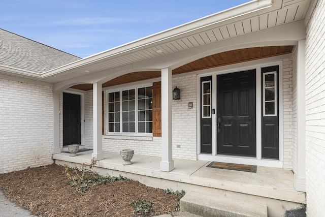 10159 E Rivershore Dr SE, Alto, MI 49302 - view of exterior entry featuring a porch, a shingled roof, and brick siding