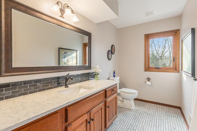 10159 E Rivershore Dr SE, Alto, MI 49302 - bathroom featuring vanity, toilet, tile patterned floors, baseboards, and backsplash