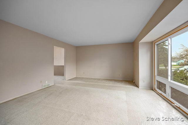 spare room featuring baseboards, light carpet, and visible vents