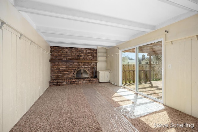 unfurnished living room with carpet, wooden walls, a fireplace, and beamed ceiling
