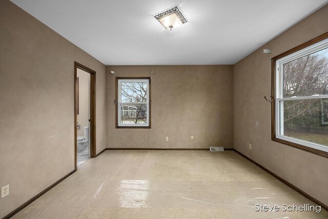empty room featuring light colored carpet, baseboards, and visible vents