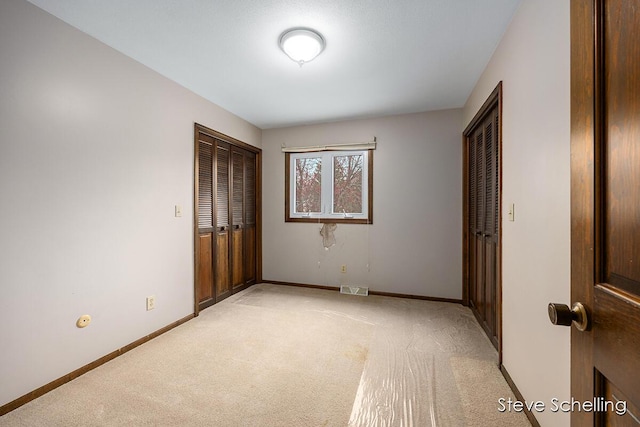 unfurnished bedroom with light colored carpet, baseboards, visible vents, and a closet