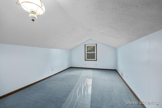 additional living space with carpet flooring, a textured ceiling, vaulted ceiling, and baseboards