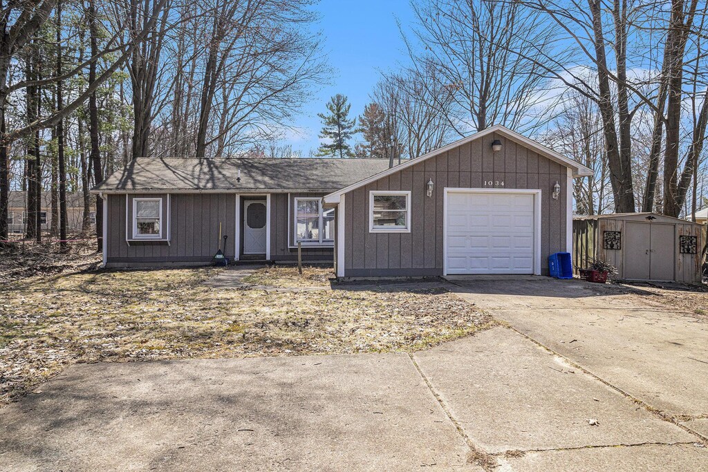 1034 Leo St, Fremont, MI 49412 - ranch-style home featuring board and batten siding, driveway, a shed, and an outdoor structure