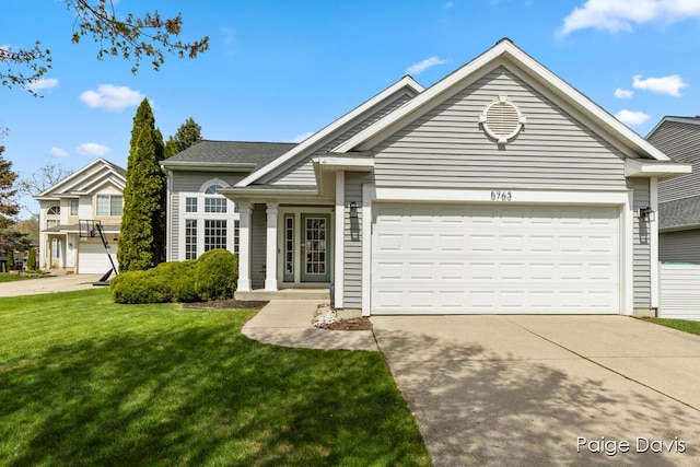 view of front of home with an attached garage, a front lawn, and driveway