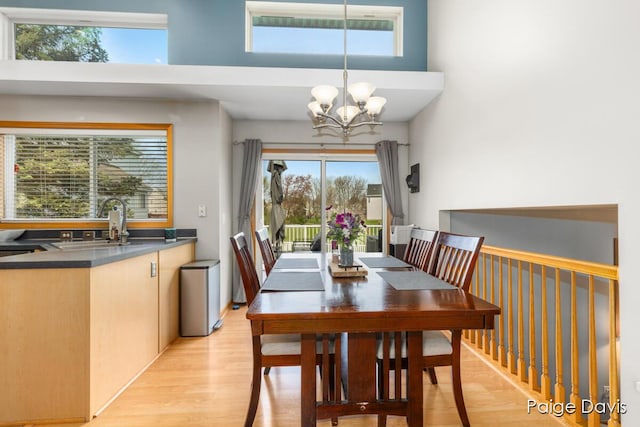 dining area featuring an inviting chandelier, a towering ceiling, and light wood-type flooring