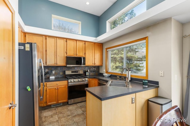 kitchen featuring visible vents, appliances with stainless steel finishes, dark countertops, a sink, and a peninsula