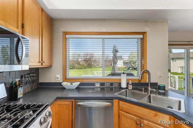 kitchen featuring a sink, appliances with stainless steel finishes, dark countertops, and a healthy amount of sunlight