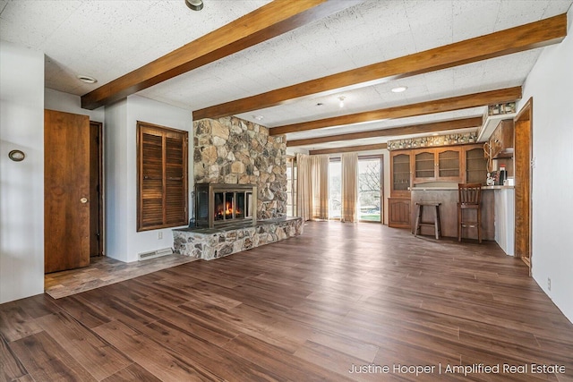 1220 W Green St, Hastings, MI 49058 - unfurnished living room with wood finished floors, visible vents, a stone fireplace, and beam ceiling