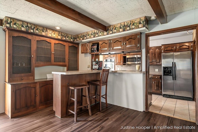 1220 W Green St, Hastings, MI 49058 - kitchen with a breakfast bar, light countertops, light wood-style floors, beam ceiling, and stainless steel appliances