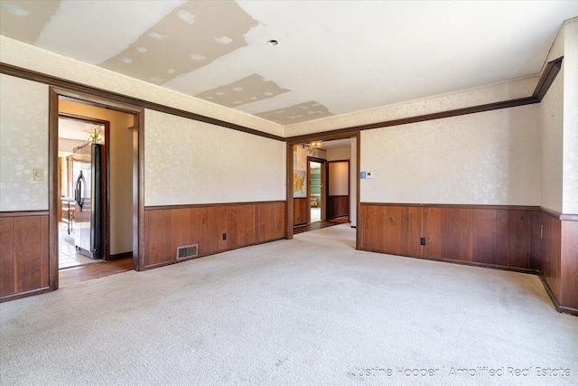 1220 W Green St, Hastings, MI 49058 - unfurnished room featuring wood walls, wainscoting, visible vents, and carpet floors