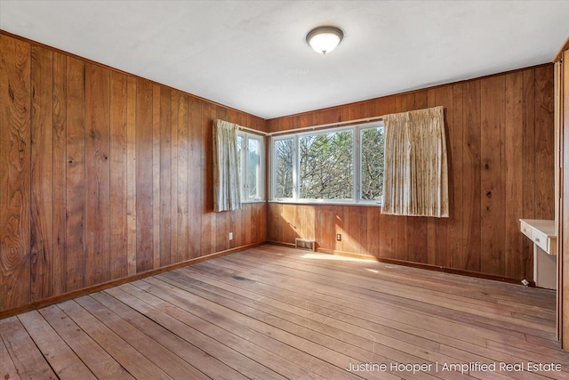 1220 W Green St, Hastings, MI 49058 - empty room with wooden walls, visible vents, and hardwood / wood-style flooring