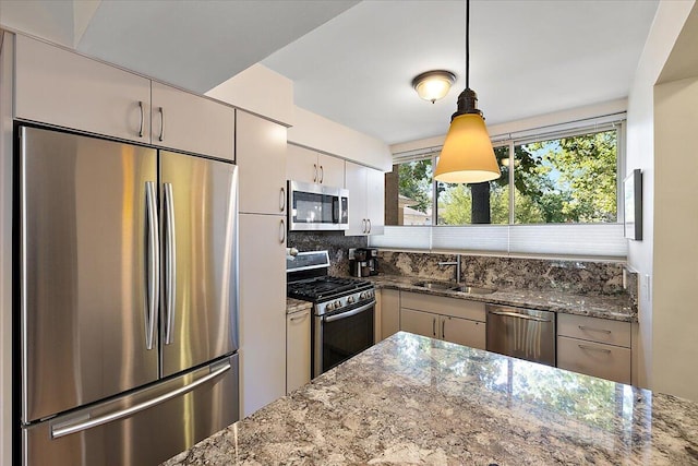 1118 Stafford Pl, Detroit, MI 48207 - kitchen featuring dark stone counters, tasteful backsplash, appliances with stainless steel finishes, a sink, and hanging light fixtures