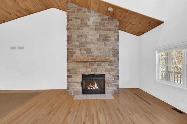 unfurnished living room featuring visible vents, wooden ceiling, wood finished floors, and a stone fireplace